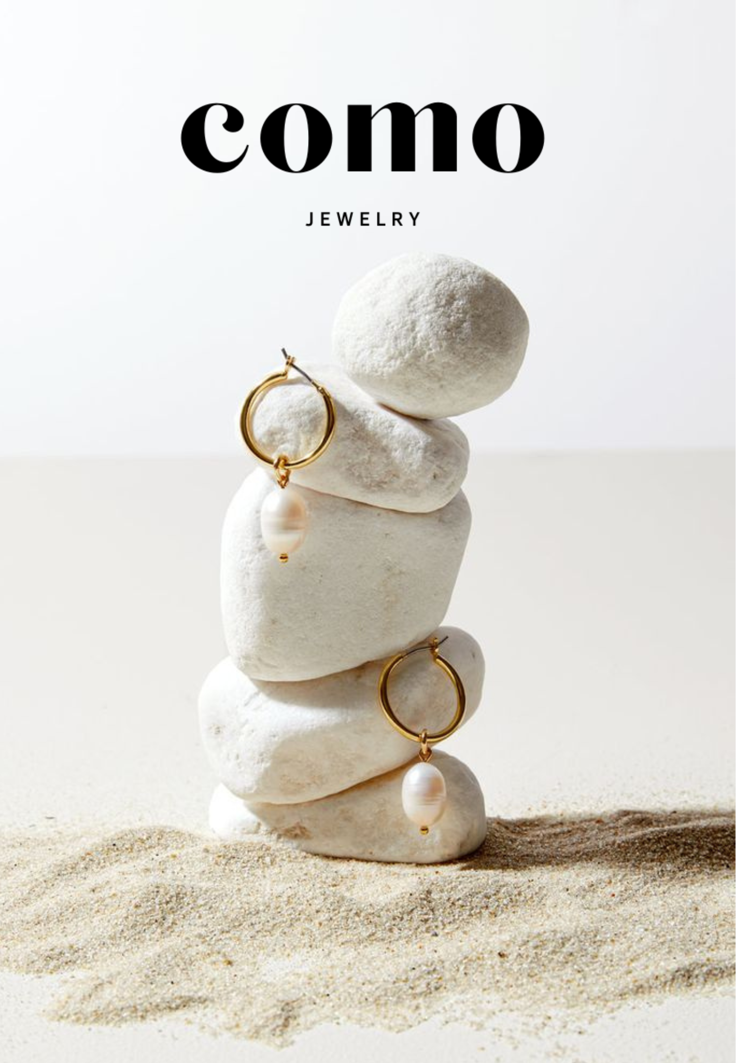 A stack of smooth white stones showcases two gold hoop earrings with pearl-like pendants. The neutral background features Como Jewelry Dāvanu karte, highlighting this elegant juveliertērauda rotas.