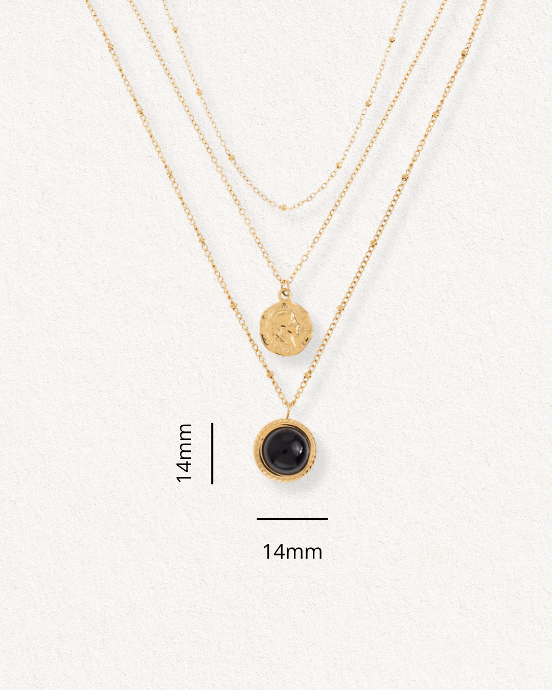 Trīsslāņains "Kaklarota - Nakts simboli" no Como Jewelry uz krēmkrāsas fona: īsākā ir vienkārša ķēdīte, vidū ir apaļš piekariņš ar faktūru, bet garākajā ir 14 mm melns akmens piekariņš.