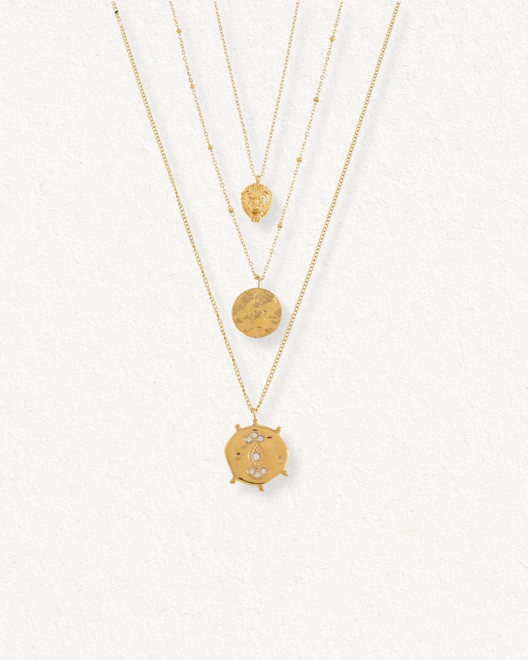 Kaklarotu komplekts Gaismas kārtas no Como Jewelry - trīs līmeņu juveliertērauda kaklarota ar unikāliem piekariņiem: lauvas galva, teksturēts disks un medaļons ar pusmēnesi un zvaigznēm. Ūdensizturīga, lieliski piemērota ikdienai.