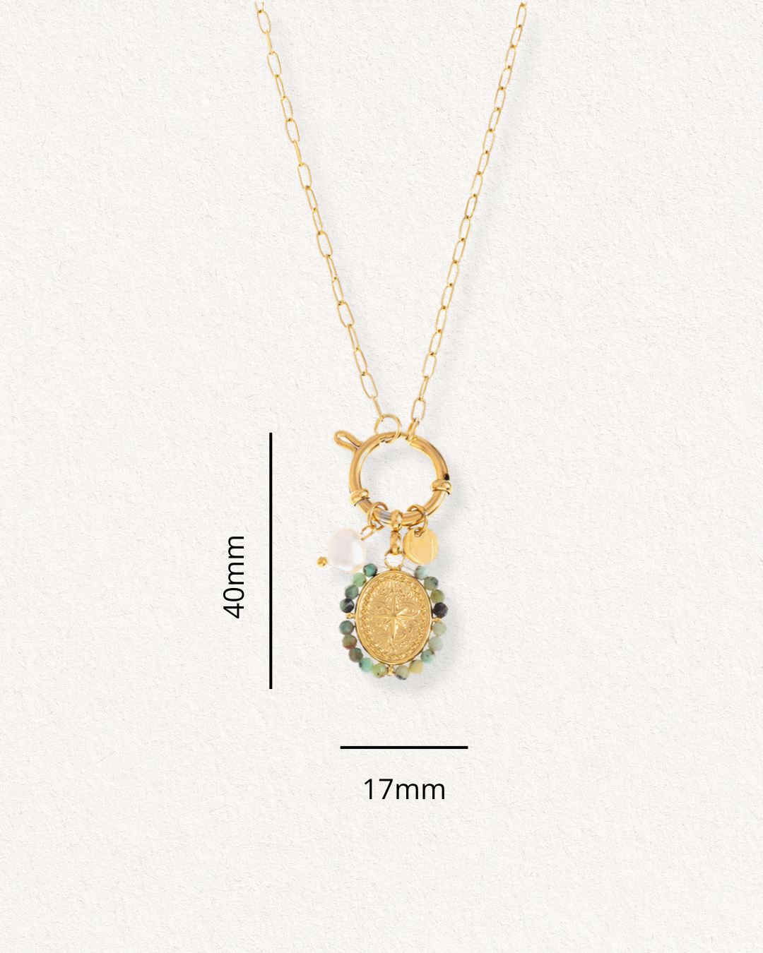 Kaklarota - Vēja roze by Como Jewelry ir moderna, antialerģiska zelta kaklarota ar ovālu kulonu (40 mm x 17 mm) un daudzkrāsainām pērlītēm, kas ir ideāli piemērota jutīgai ādai. Attēlots uz gaišas faktūras fona.