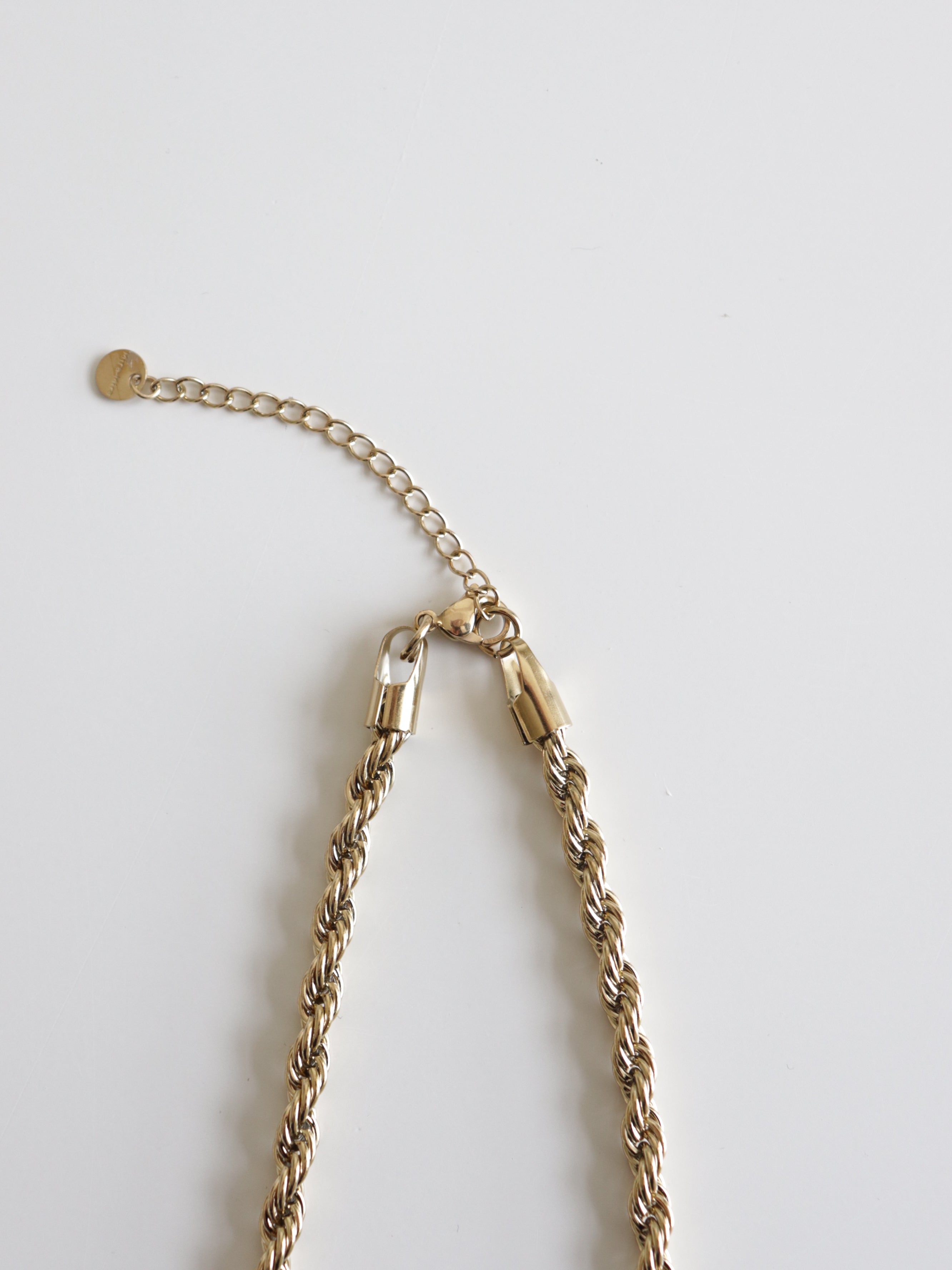 Kaklarota - Zelta ķēde no Como Jewelry ar mūsdienīgu juveliertērauda dizainu, zelta virvju pinumu, karabīnes aizdari un pagarinātāju novietota uz balta fona.