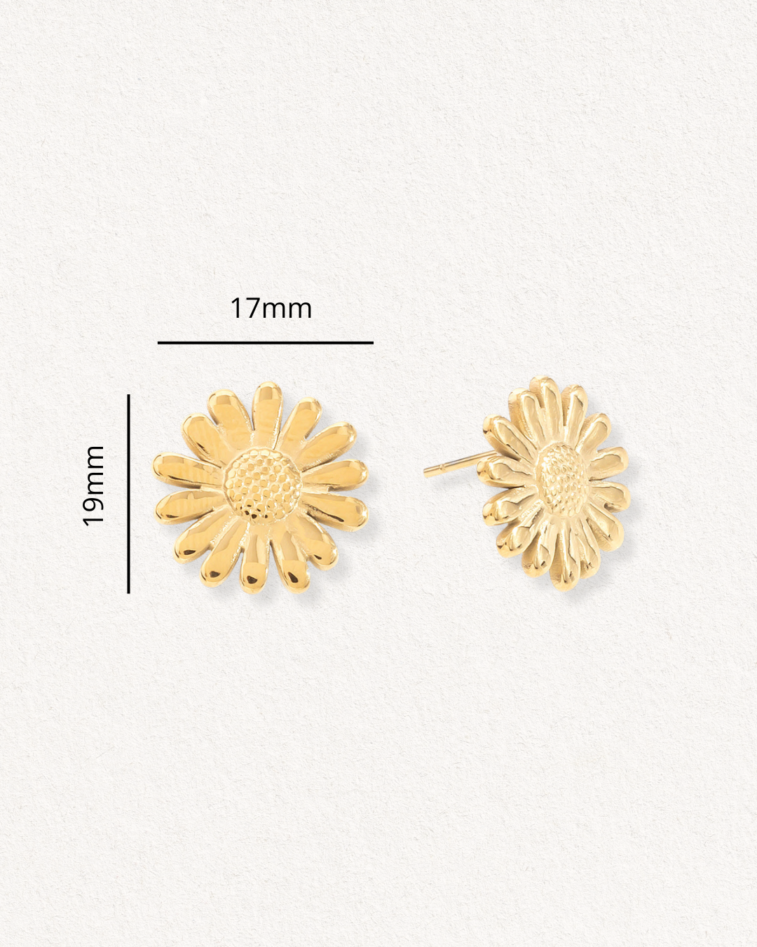 Como Jewelry "Mazie auskari - Margrietiņa" ir zieda formas auskari ar fakturētiem ziedlapiņām un centru, kas izgatavoti no hipoalerģiska apzeltīta tērauda. To izmēri ir 17 mm platumā un 19 mm augstumā, un tie ir attēloti gan no priekšpuses, gan no sāniem uz nebalta fona.