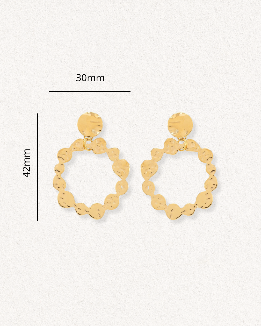 Como Jewelry "Auskari - Saules Rats" ir zelta riņķīši ar viļņainu, apaļu dizainu un zelta pārklājumu, katrs ar izmēriem 42 x 30 mm, uz balta fakturēta fona.