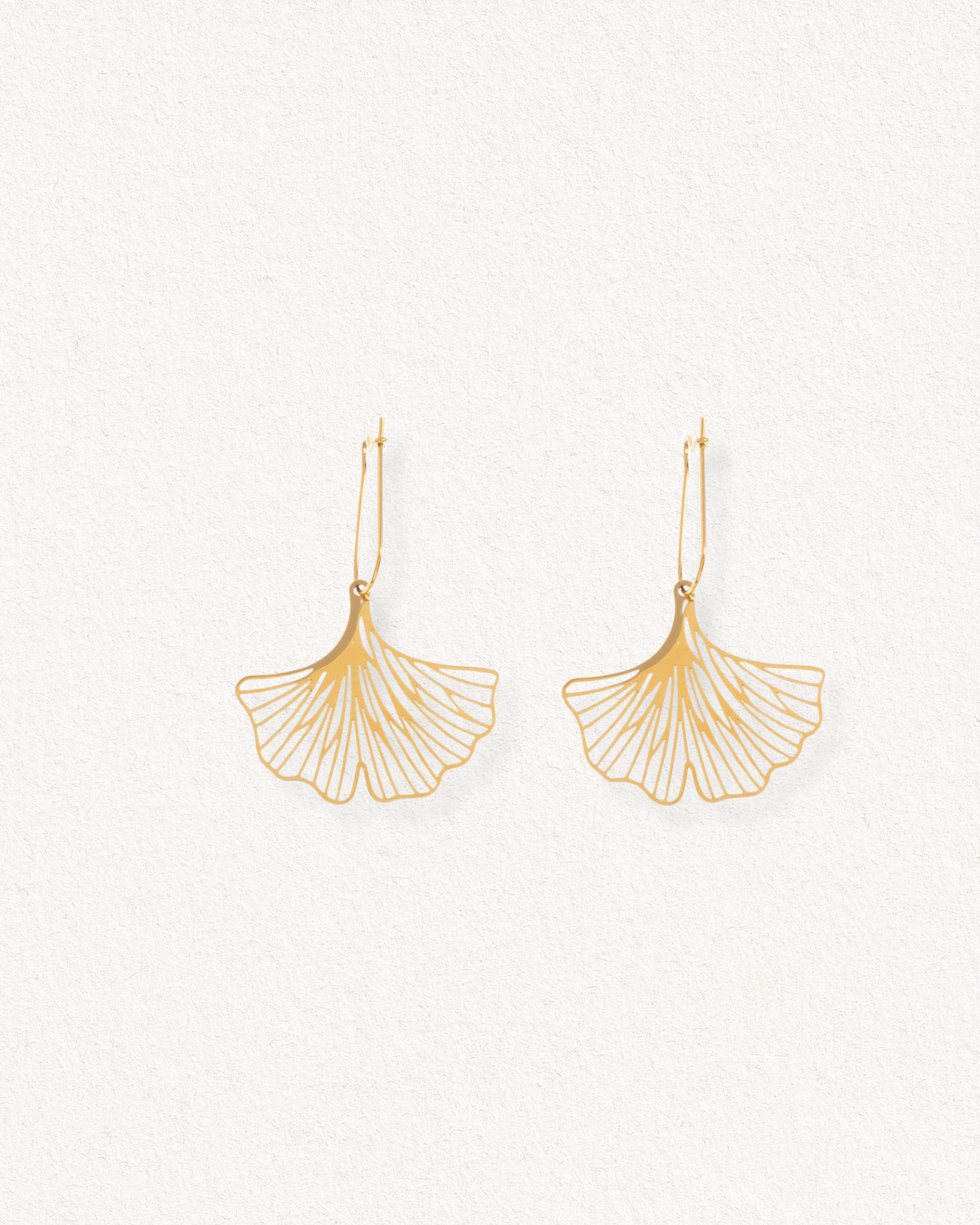 Auskari - Ginkgo: gold earrings featuring a delicate fan-shaped design inspired by ginkgo leaves, shown on a light textured background.