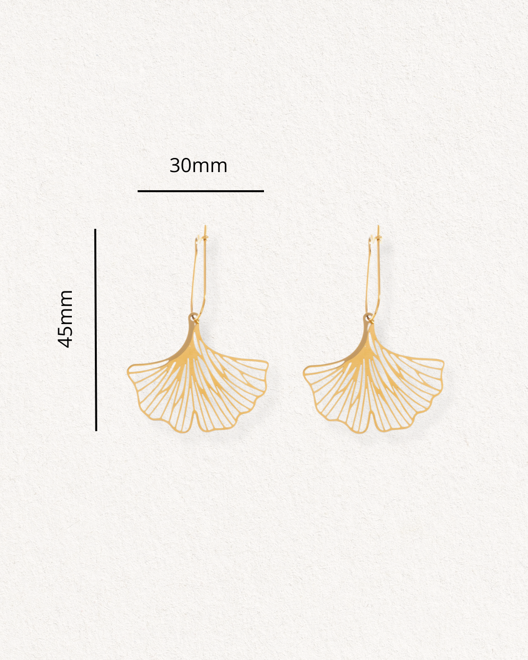 Como Jewelry Auskari - Ginkgo auskari, kas veidoti kā ginkgo lapas, izmēri ir 45 mm x 30 mm, un tiem ir smalkas līnijas detaļas, kas skaisti imitē lapu dzīslas. Tie izvietoti uz gaišas faktūras fona.