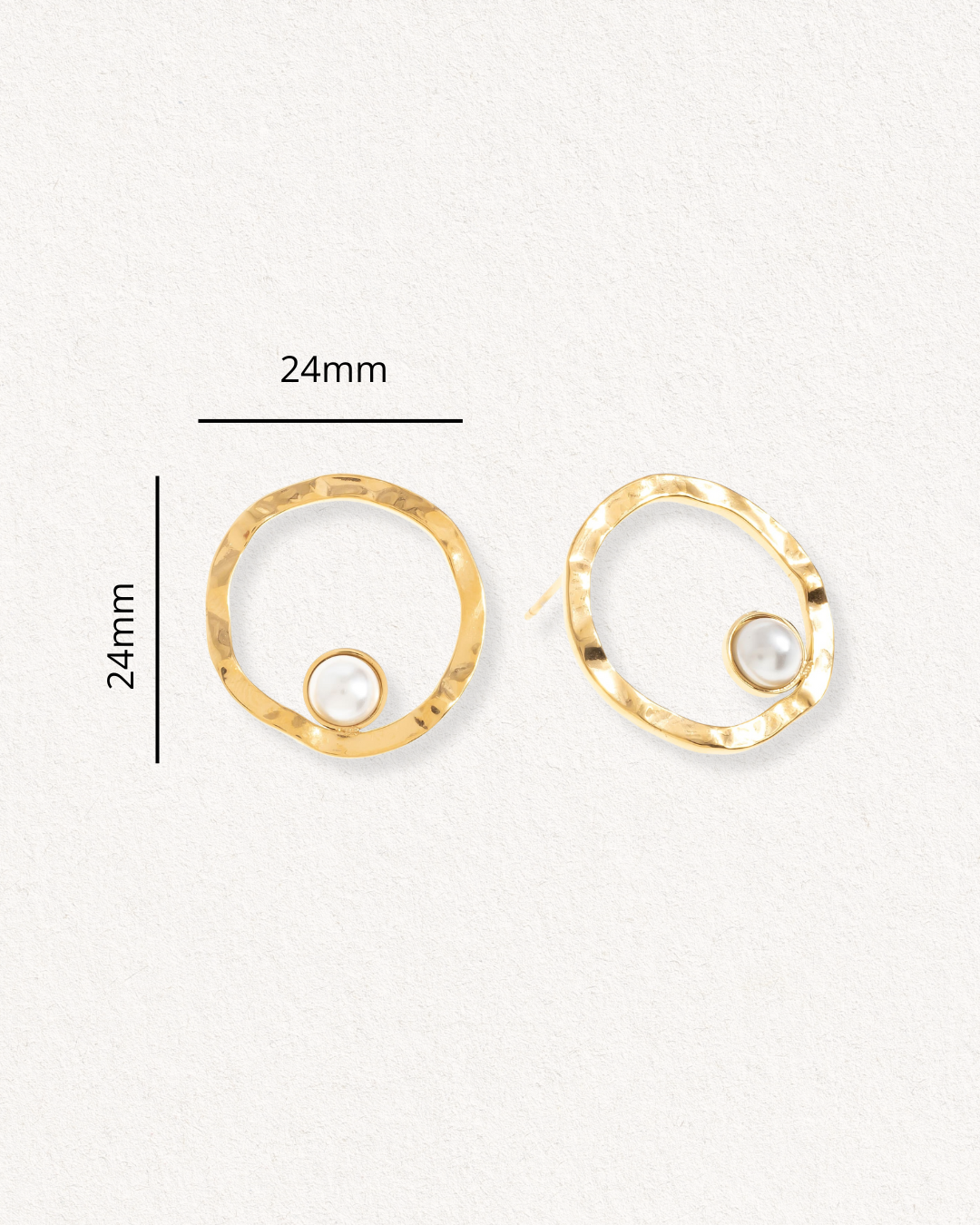 Mazie auskari - Rietošā pērle by Como Jewelry: mūsdienīgi kalti zeltīti apļi ar maziem pērļu akcentiem, katrs aplis 24 mm augsts un plats, uz gaišas faktūras fona.