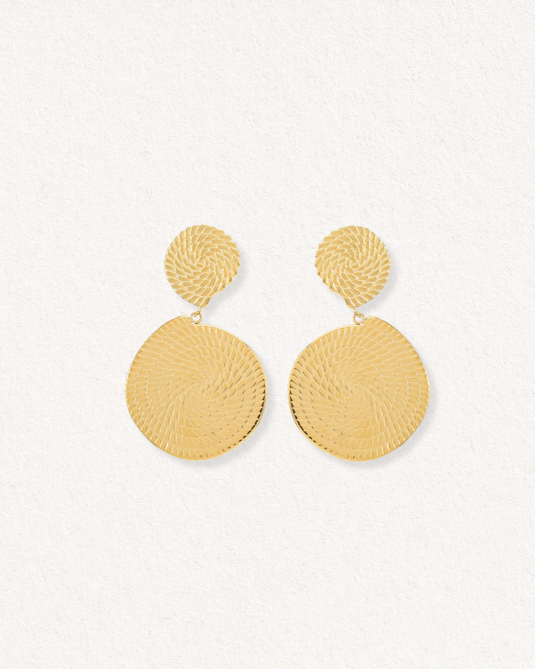 Auskari - Grācija: sieviešu zelta pārklājuma juveliertērauda auskari ar spirālveida rakstu, nelielu apaļu puļķīti un lielāku piekariņu, teksturēta fonā.