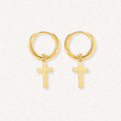 Como Jewelry "Auskari - ar krustu" ir zelta riņķveida auskari ar maziem zelta krustiņu piekariņiem, kas izvietoti uz gaišas faktūras fona.