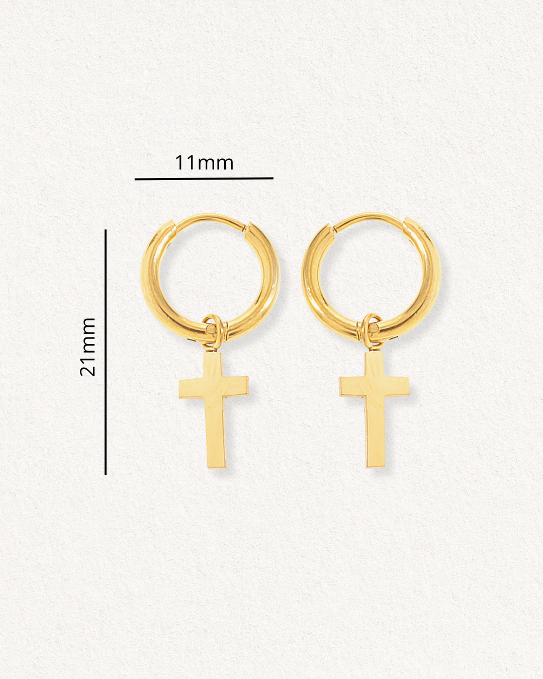 Como Jewelry Auskari - ar krustu: mūsdienīgi zelta riņķveida auskari ar maziem krusta piekariņiem, katrs 21 mm garš un 11 mm plats. Attēlots uz gaišas faktūras fona ar mērījumu līnijām mērogam. Ideāli antialerģiski auskari ikdienai.