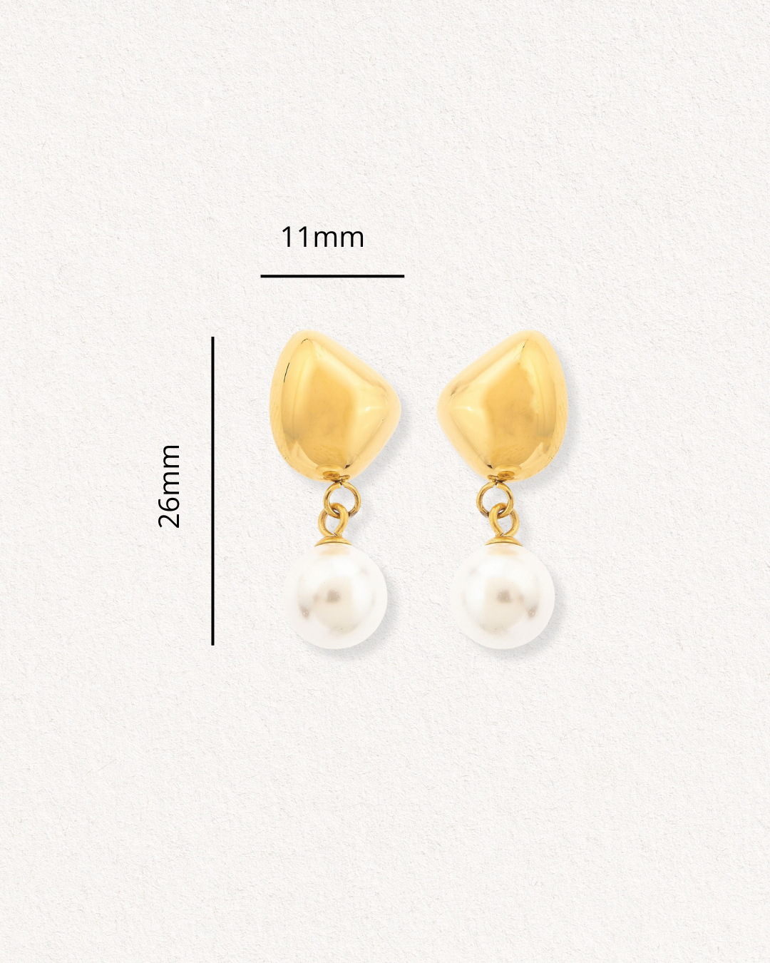 Mazie auskari - Rīta rasa by Como Jewelry: zelta pilienu auskari ar neregulāras formas tapām un piekārtām baltām pērlēm, 26 mm x 11 mm, hipoalerģiski auskari, ideāli jutīgām ausīm. Izkārtotas uz gaišas faktūras fona.