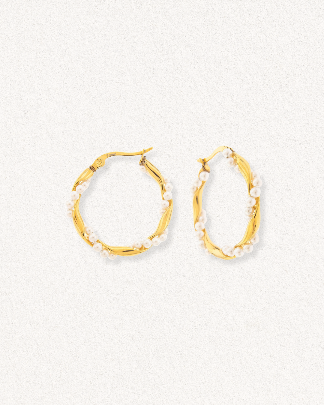 Como Jewelry Mazie auskari - Pērļu vainags: mazas baltas pērlītes apvij vītā zelta dizainu, kas izcelts uz gaišas faktūras fona.