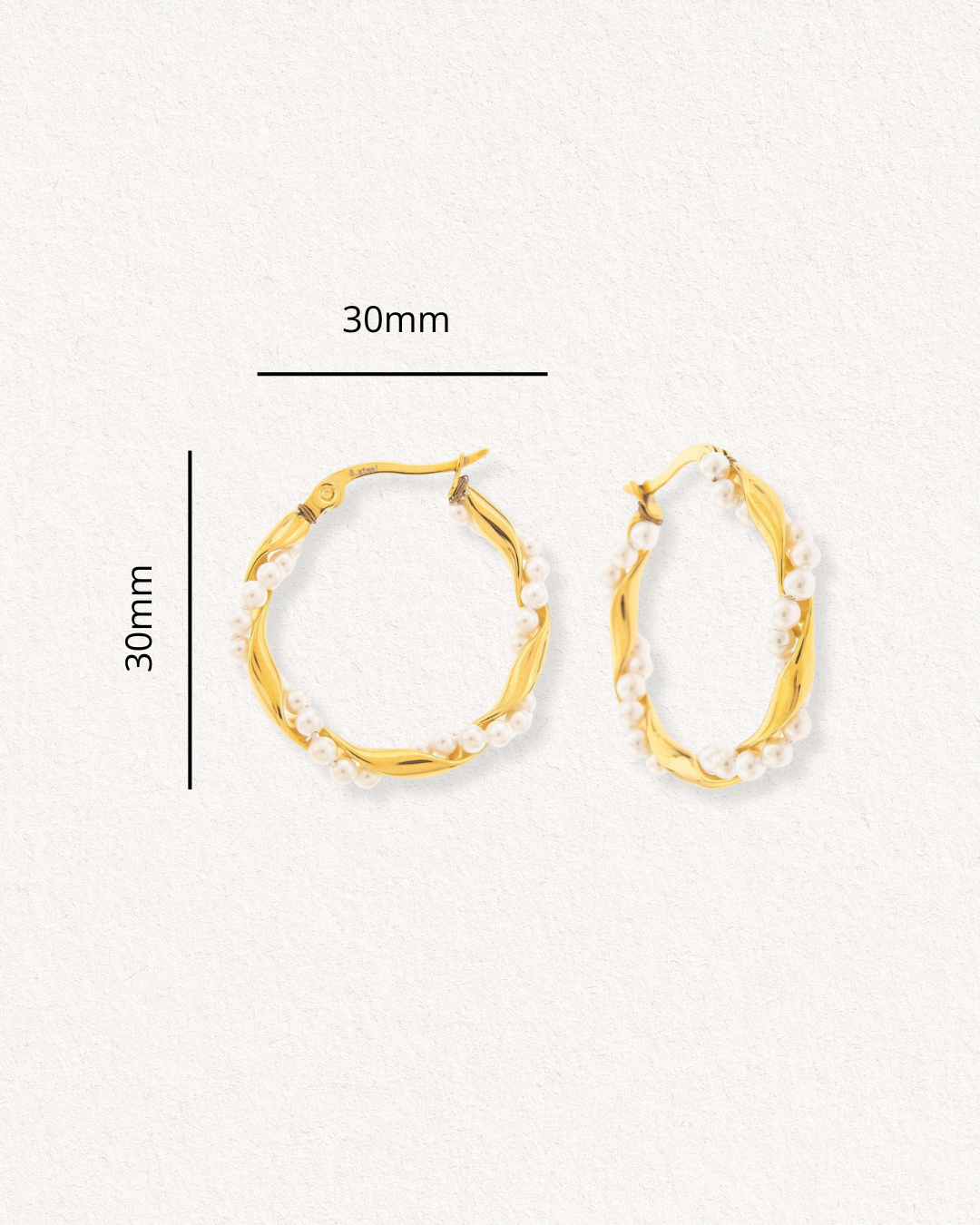 Como Jewelry Mazie auskari - Pērļu vainagi ir apzeltīti nerūsējošā tērauda riņķveida auskari, ko rotā mazas baltas pērlītes. Katra auskara augstums un platums ir 30 mm, un tie novietoti uz fakturēta balta fona.