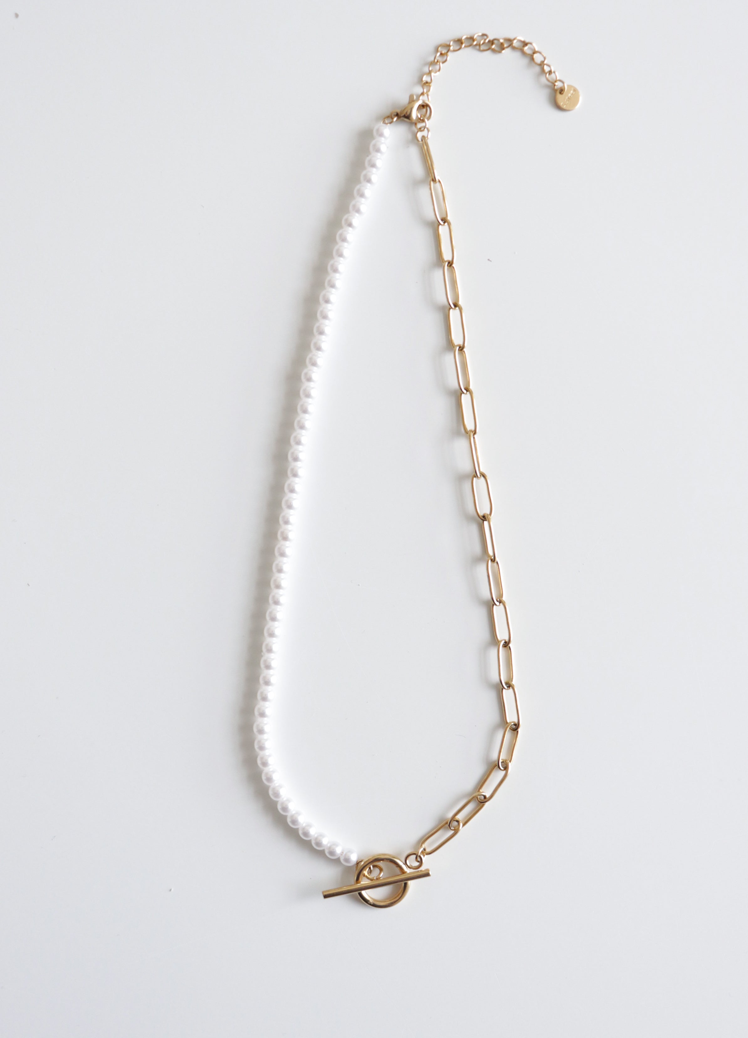 Como Jewelry "Kaklarota - ar pērlēm" - juveliertērauda kaklarota ar pusi baltām pērlēm, pusi zelta ķēdes posmiem un apaļu zelta piespraudi, attēlota uz balta fona. Antialerģiska rotaslieta elegantam stilam.