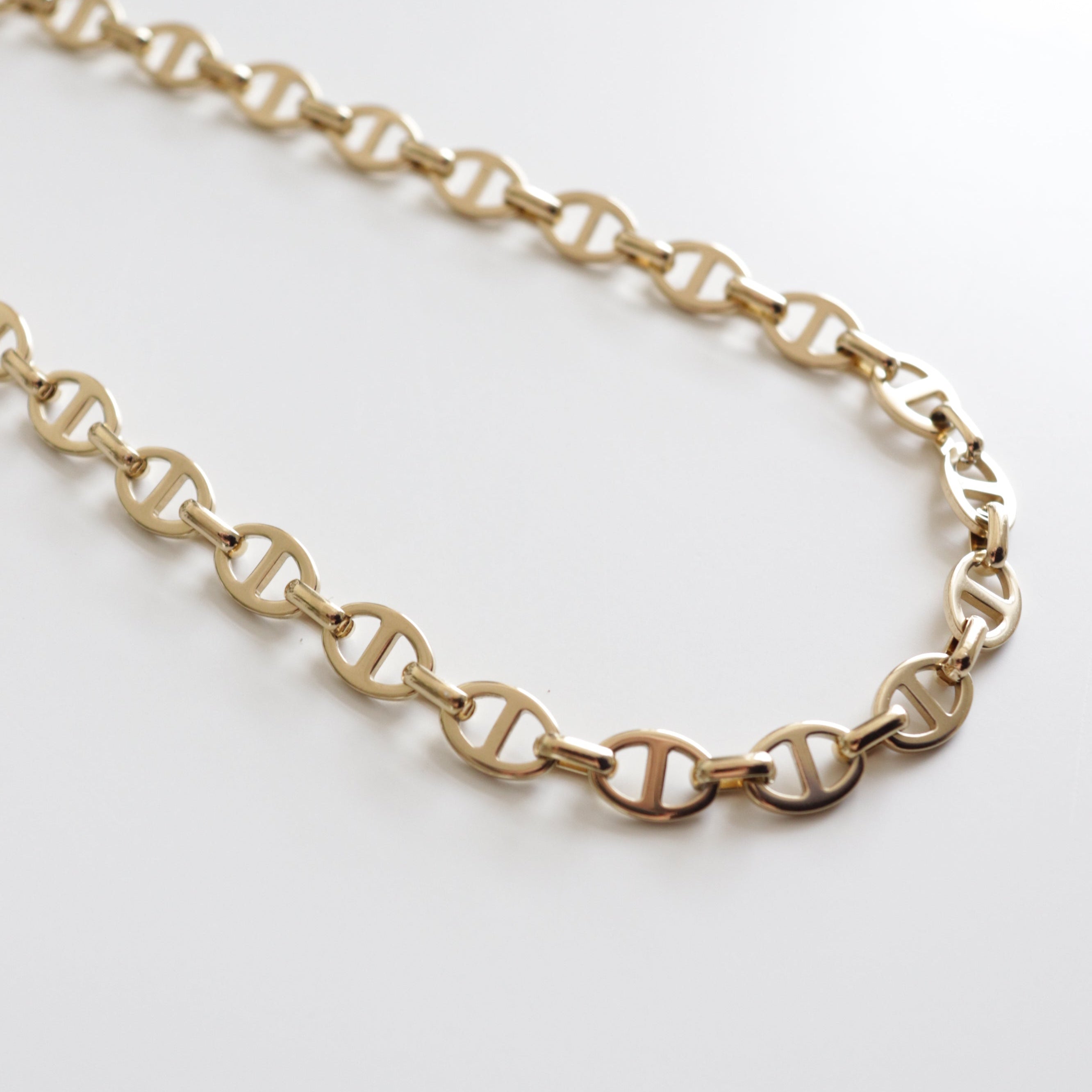 Kaklarota - Zelta ķēde no Como Jewelry: sieviešu antialerģiska zelta ķēde ar ovālām pozmām un horizontālu stieni katrā, piemērota ikdienas valkāšanai. Displejā uz balta fona.