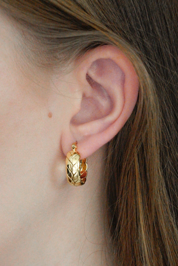 Sievietes auss tuvplānā, kurai ir Como Jewelry Mazie auskari - Vijums. Viņas brūnie mati ir aizķērušies aiz auss, un viņas gaišā āda izceļ auskarus, kas ideāli piemēroti jutīgai ādai.