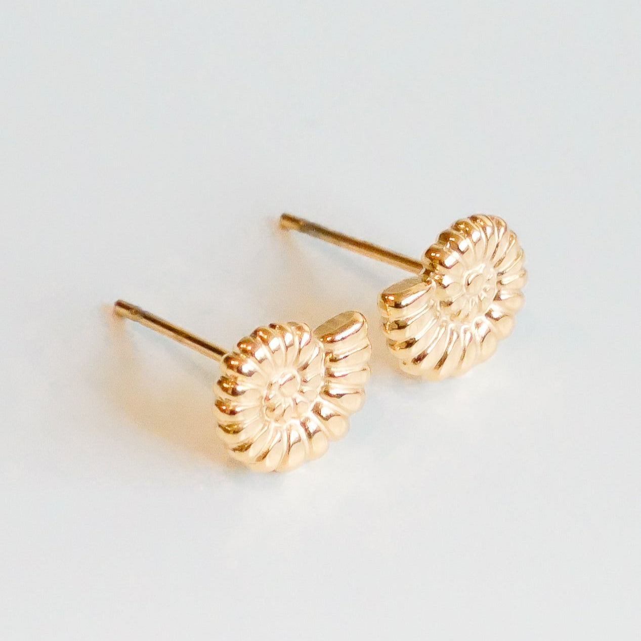 Como Jewelry Mazie auskari - Gliemežvāki: spirāles formas gliemežvāku auskari ar zelta pārklājumu, attēloti uz balta fona.