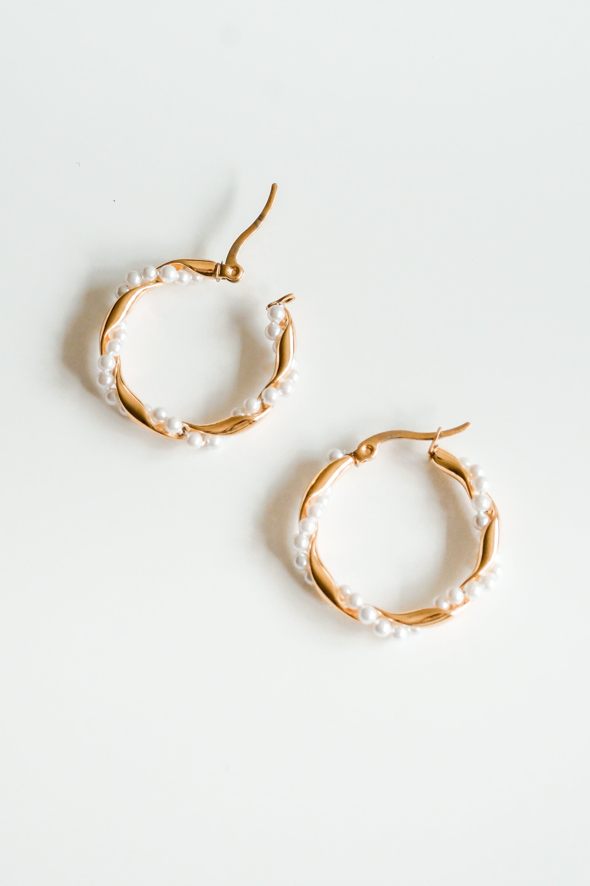 Mazie auskari - Pērļu vainags no Como Jewelry ar smalkām baltām pērlēm, darināti no nerūsējošā tērauda ar zelta pārklājumu, redzami uz vienkārša balta fona.