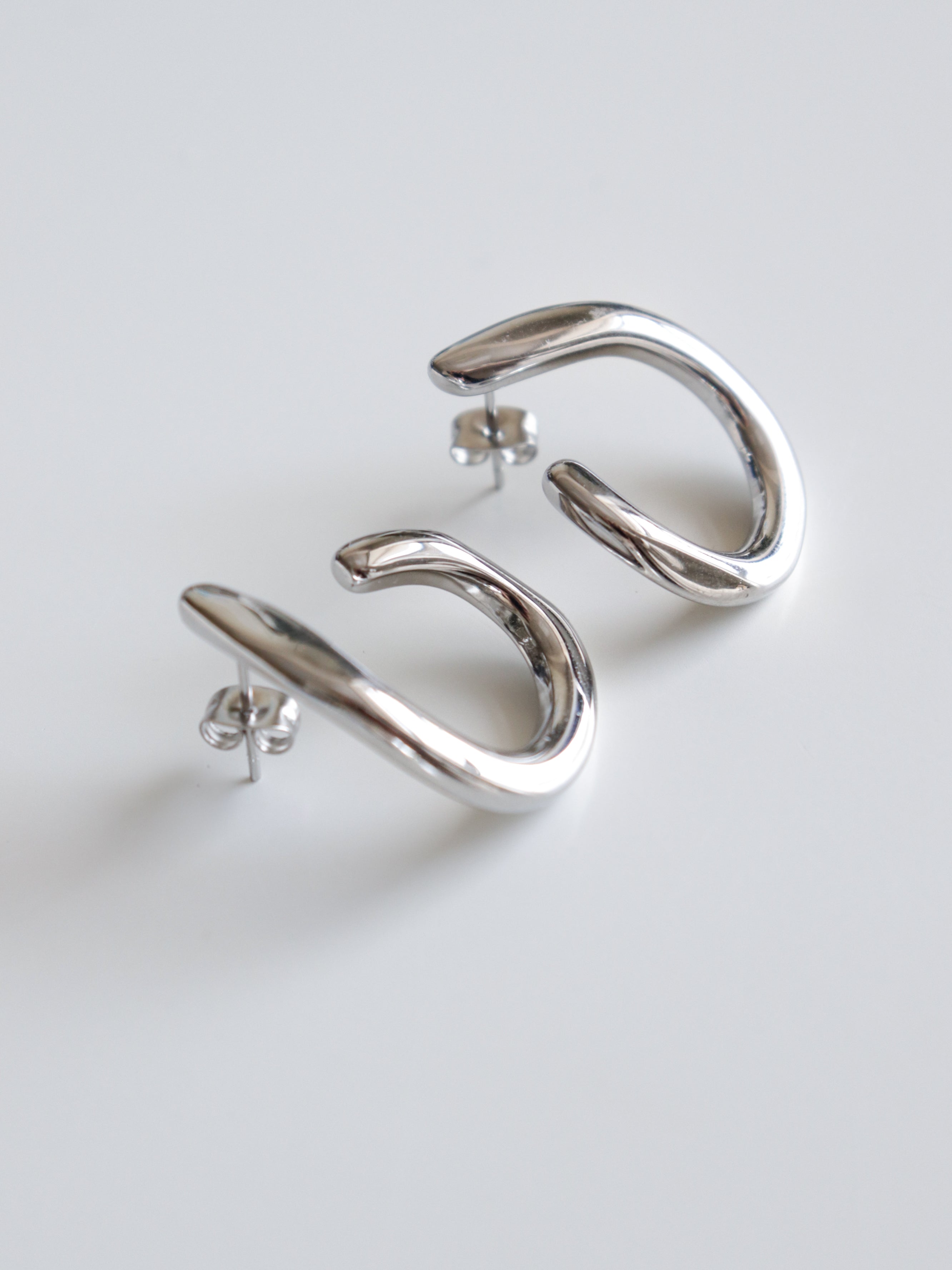 Auskari - Plūsma by Como Jewelry ir sudraba abstraktas formas riņķveida auskari ar tapām. Tie ir ūdensizturīgi, stilīgi un piemēroti jebkuram gadījumam.