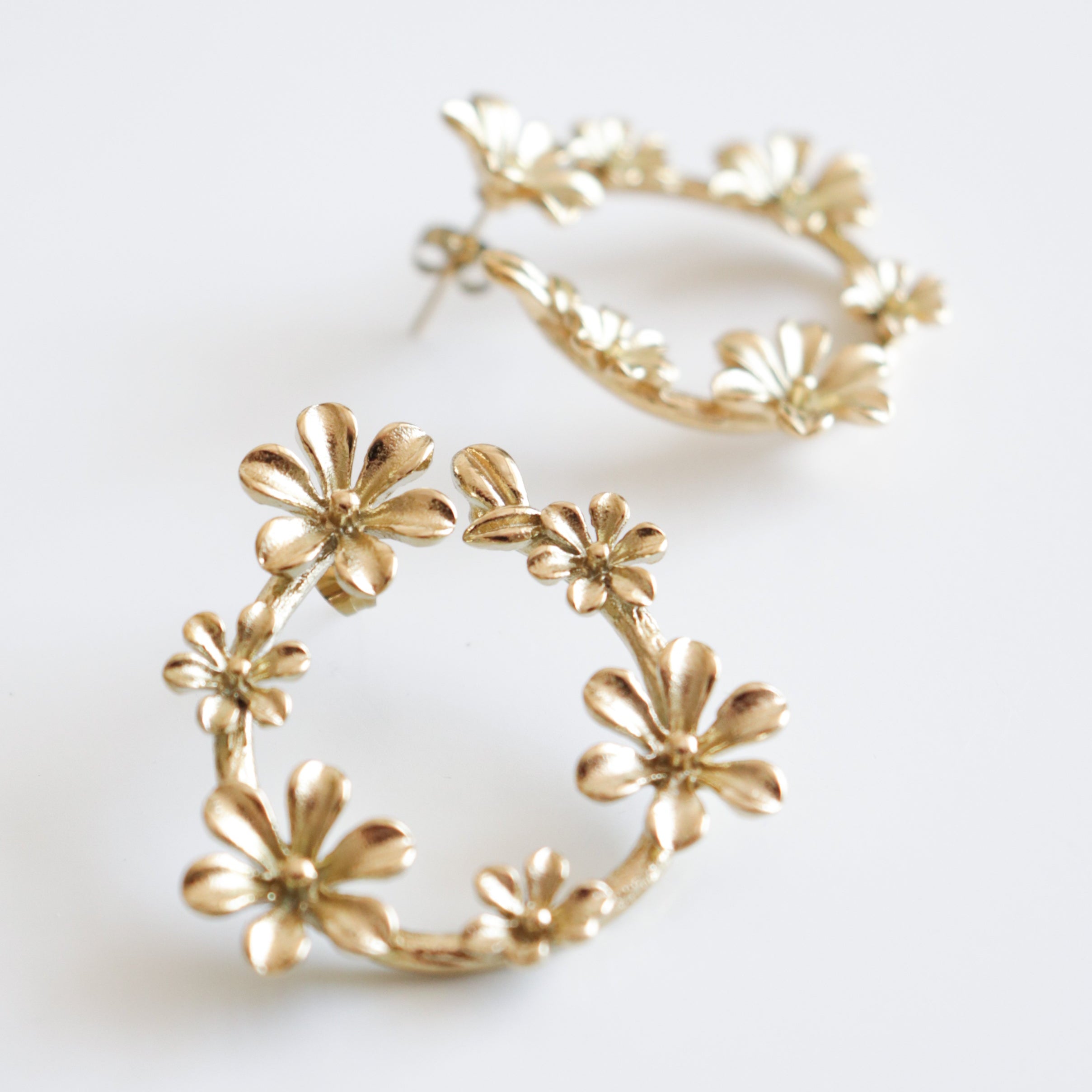 Auskari - Rokoko no Como Jewelry ar zelta pārklājumu, veidoti ziedu formā ar vairākiem maziem ziediem ap apli, izvietoti uz balta fona.