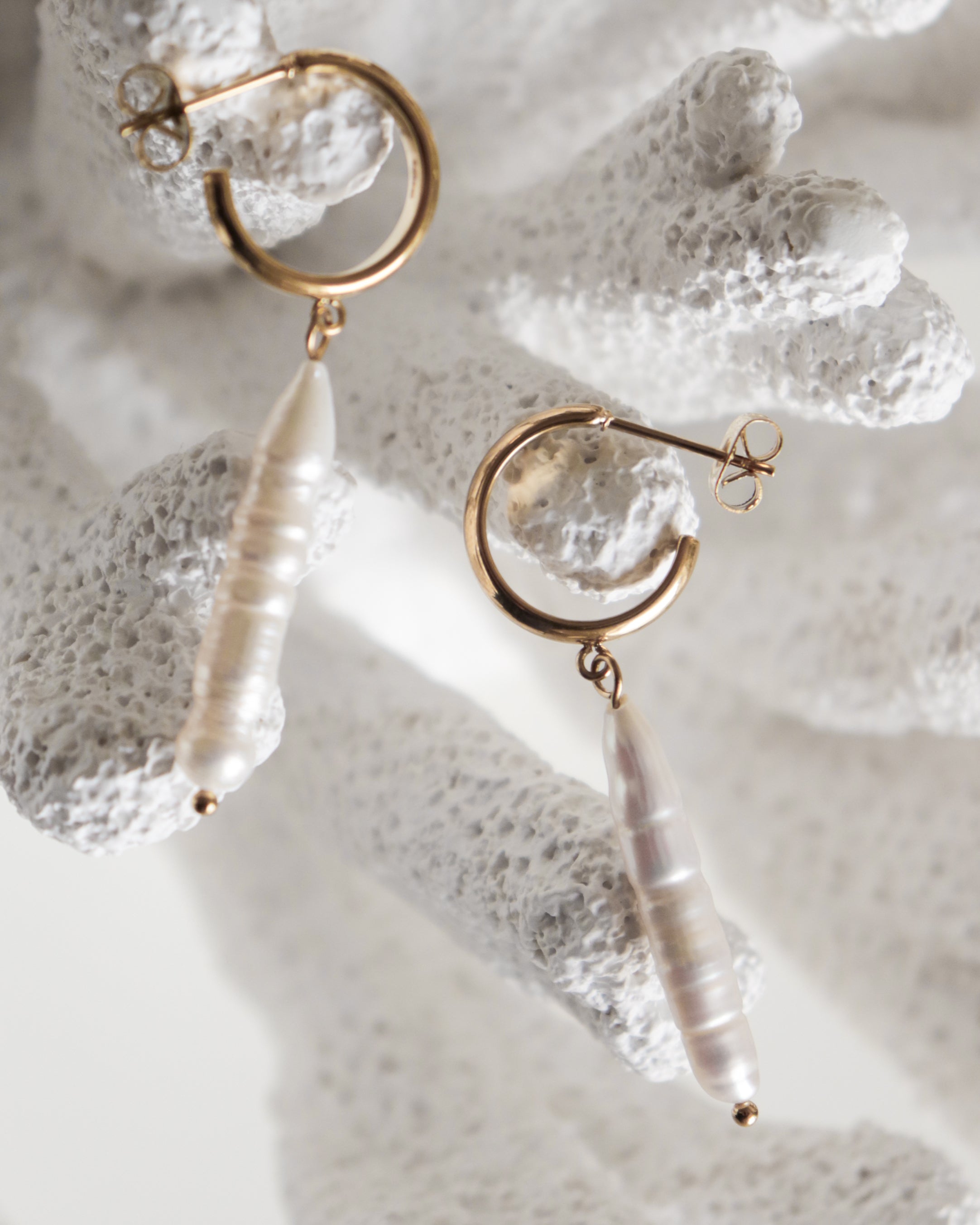 Como Jewelry Auskari - Lagūnas pērles: zelta riņķveida auskari ar iegarenām baltām saldūdens pērlēm, kas izvietotas uz koraļļu faktūras virsmas, lai iegūtu maigu un elegantu izskatu.