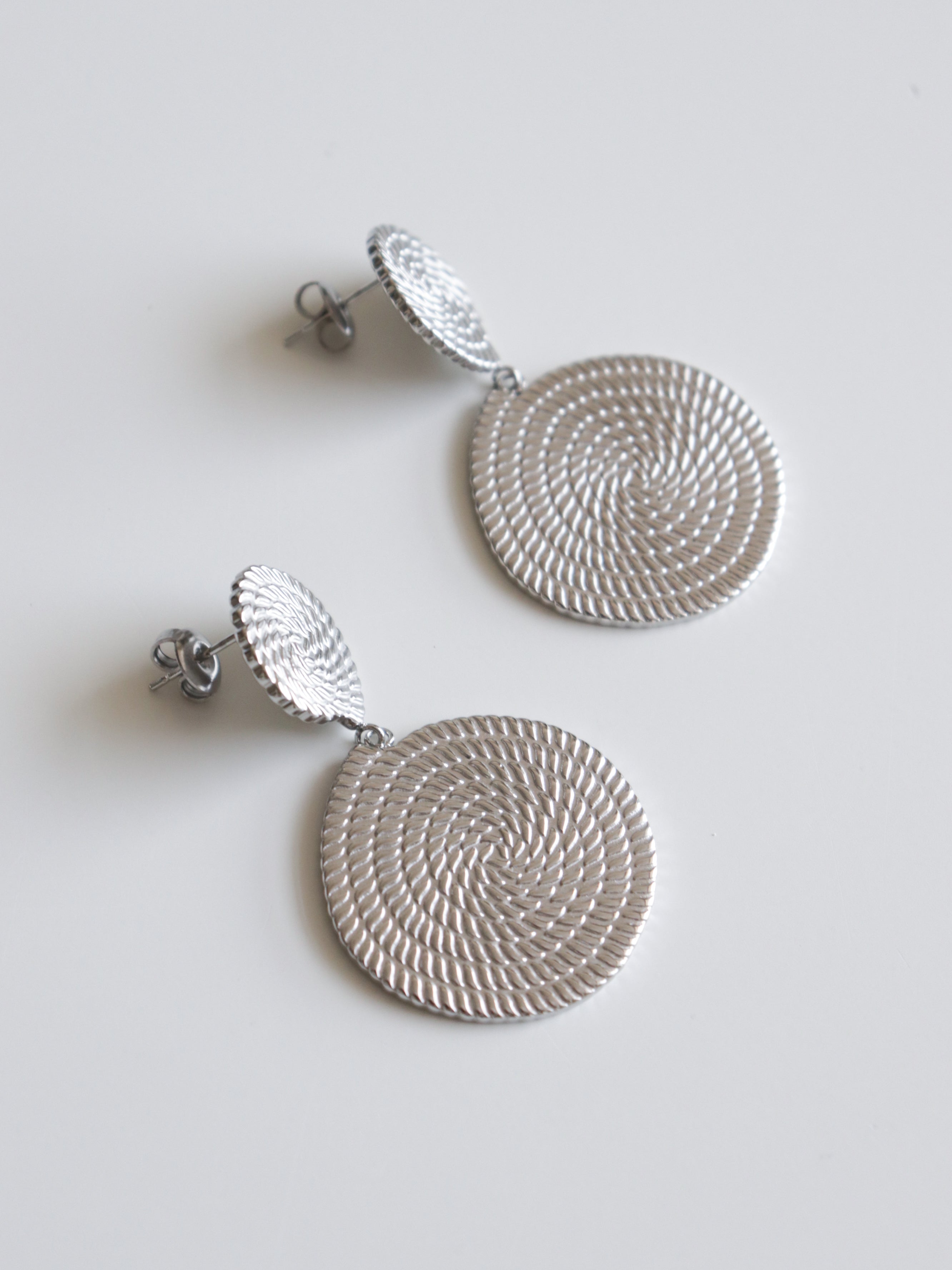 Auskari - Grācija: sieviešu sudraba auskari ar teksturētu spirāles rakstu, izgatavoti no zelta pārklājuma juveliertērauda, attēloti uz balta fona.